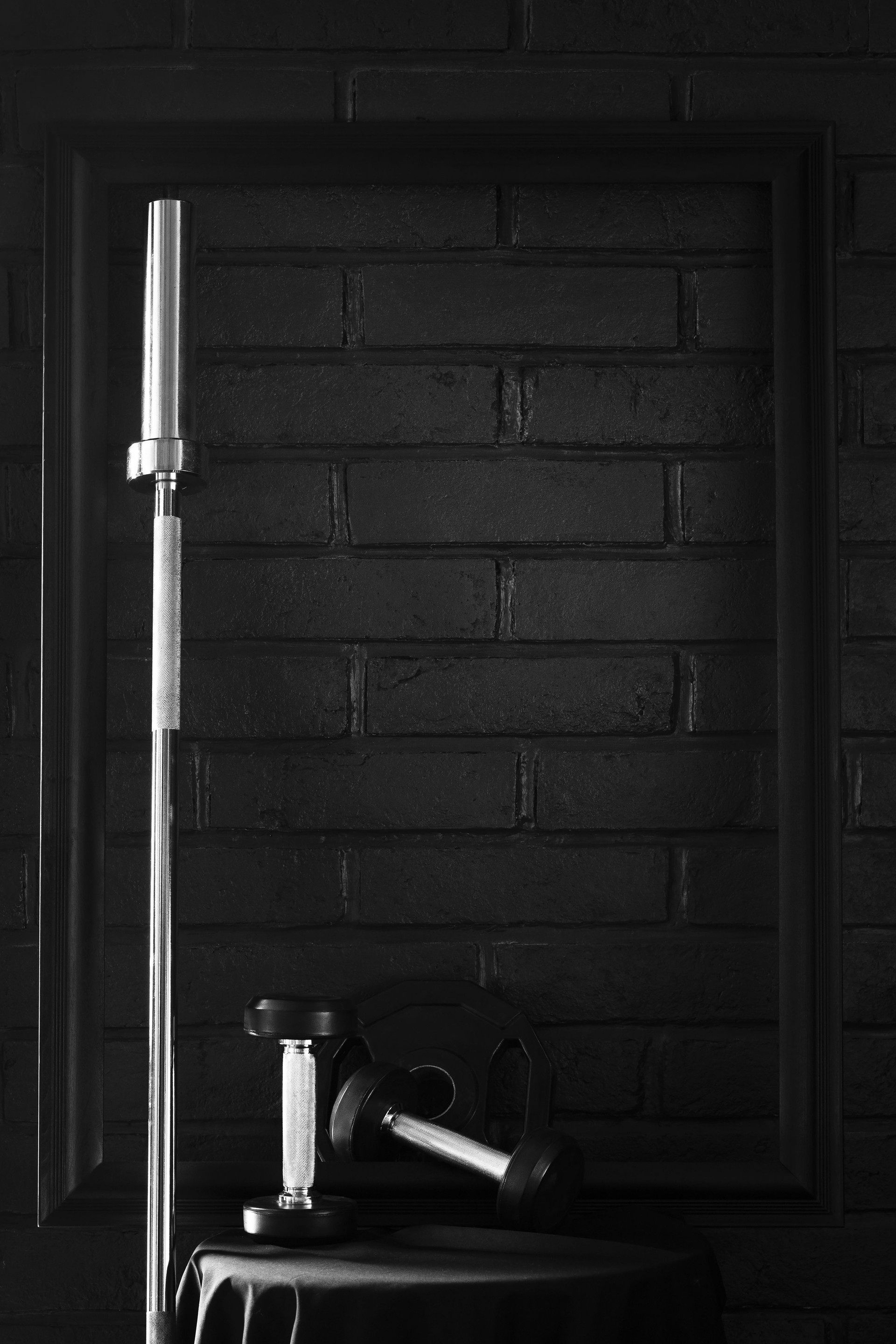 Fitness Gym background equipment barbell and dumbbells on white table with black frame dark brick wall background